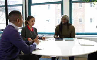 Image of three people sitting at a desk